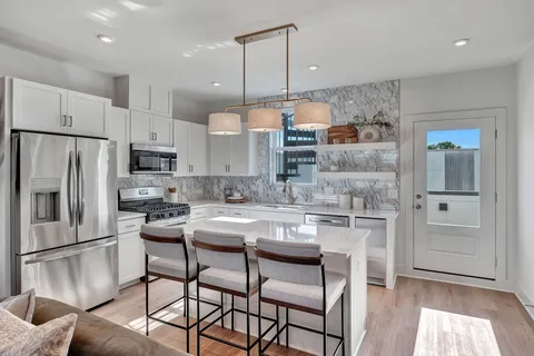 a kitchen with stainless steel appliances a refrigerator a stove a sink and chairs