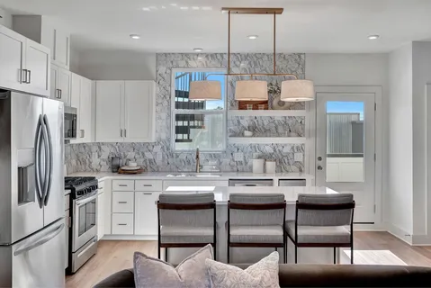 a kitchen with stainless steel appliances granite countertop a kitchen island a stove a table and chairs