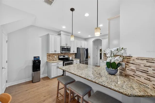 a kitchen with stainless steel appliances granite countertop a stove a sink dishwasher and a refrigerator with wooden floor