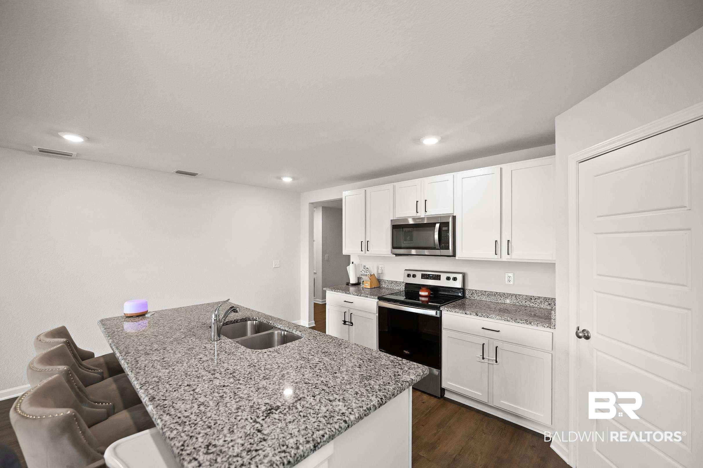 32030 Terranova Loop Lillian, AL 36549 - Photo 7 of 30 Kitchen featuring an expansive island with an undermount dual-basin sink, granite countertops, white cabinetry with contemporary hardware, stainless steel appliances, and recessed lighting