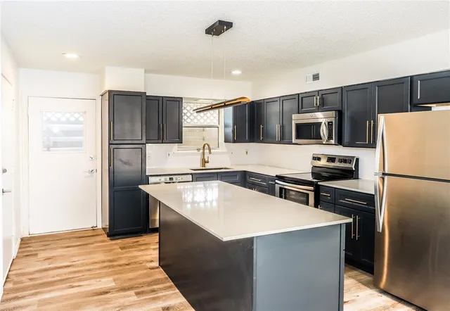 a kitchen with stainless steel appliances a refrigerator stove microwave and sink