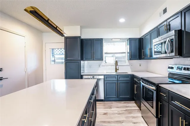 a kitchen with stainless steel appliances granite countertop a sink stove refrigerator and cabinets