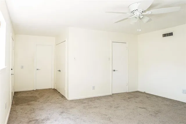 an empty room with a ceiling fan and a window