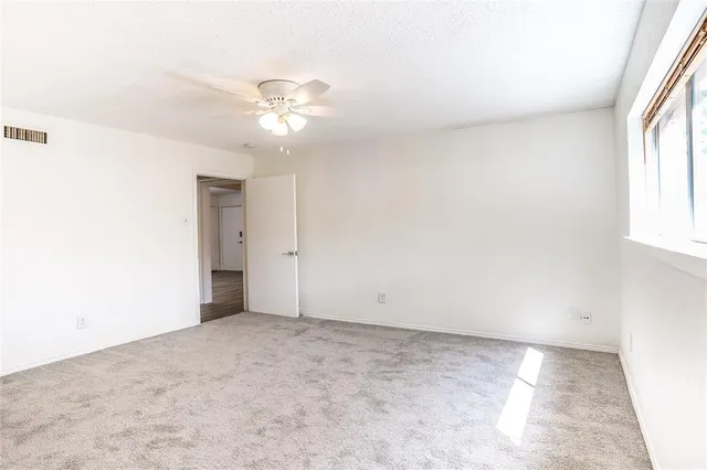 an empty room with windows and fan