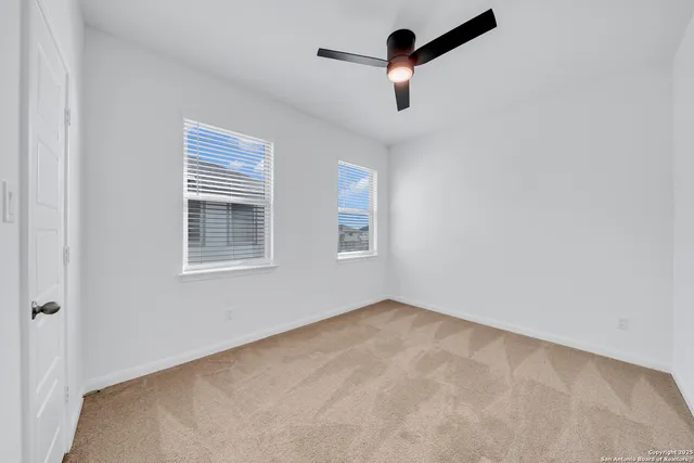 an empty room with ceiling fan and window