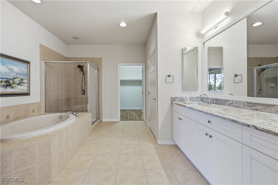 14951 Reflection Key Circle, Unit 536 Fort Myers, FL 33907 - Photo 13 of 36 a spacious bathroom with a granite countertop tub sink shower and mirror