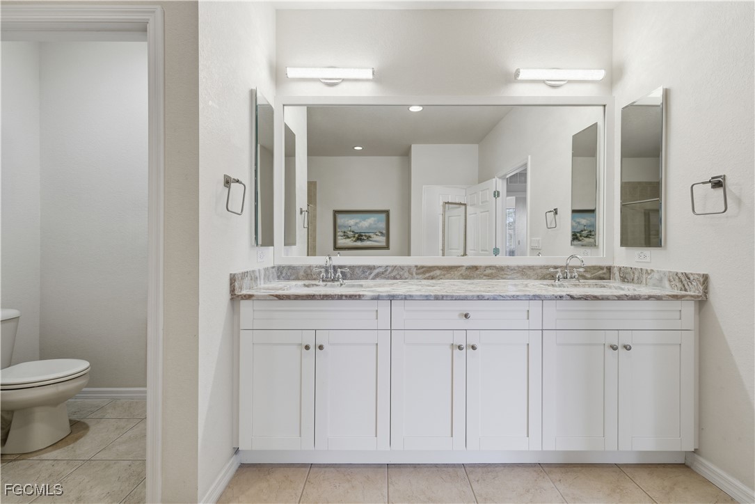 14951 Reflection Key Circle, Unit 536 Fort Myers, FL 33907 - Photo 17 of 36 a bathroom with a granite countertop sink a toilet and a mirror