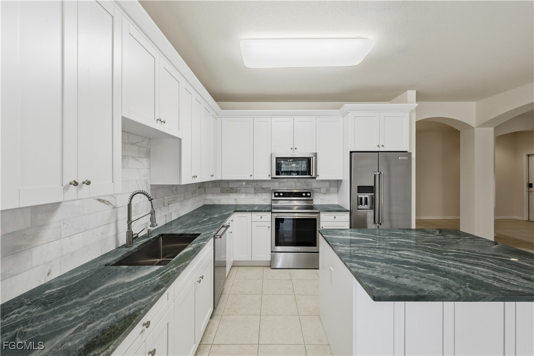 14951 Reflection Key Circle, Unit 536 Fort Myers, FL 33907 - Photo 7 of 36 a kitchen with stainless steel appliances granite countertop a sink stove and refrigerator