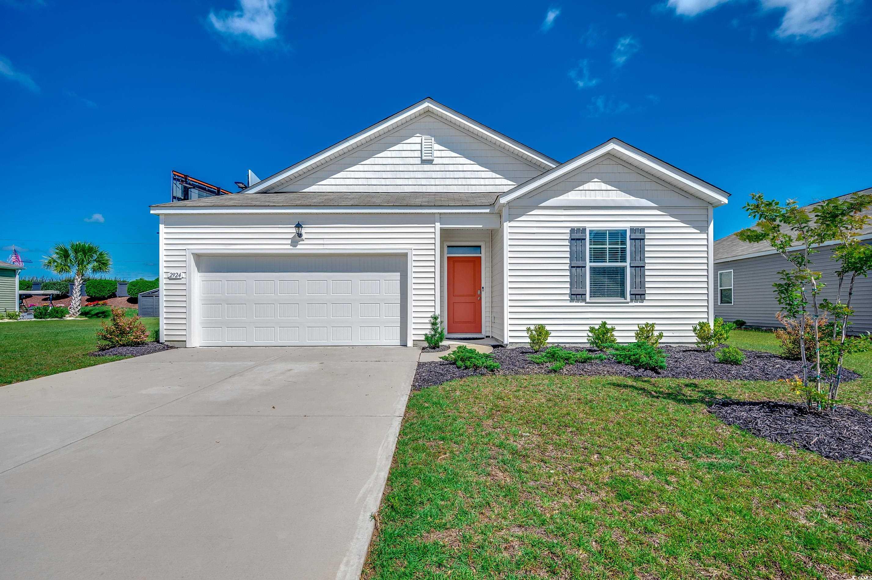 Ranch-style house featuring driveway, a garage, and a front lawn