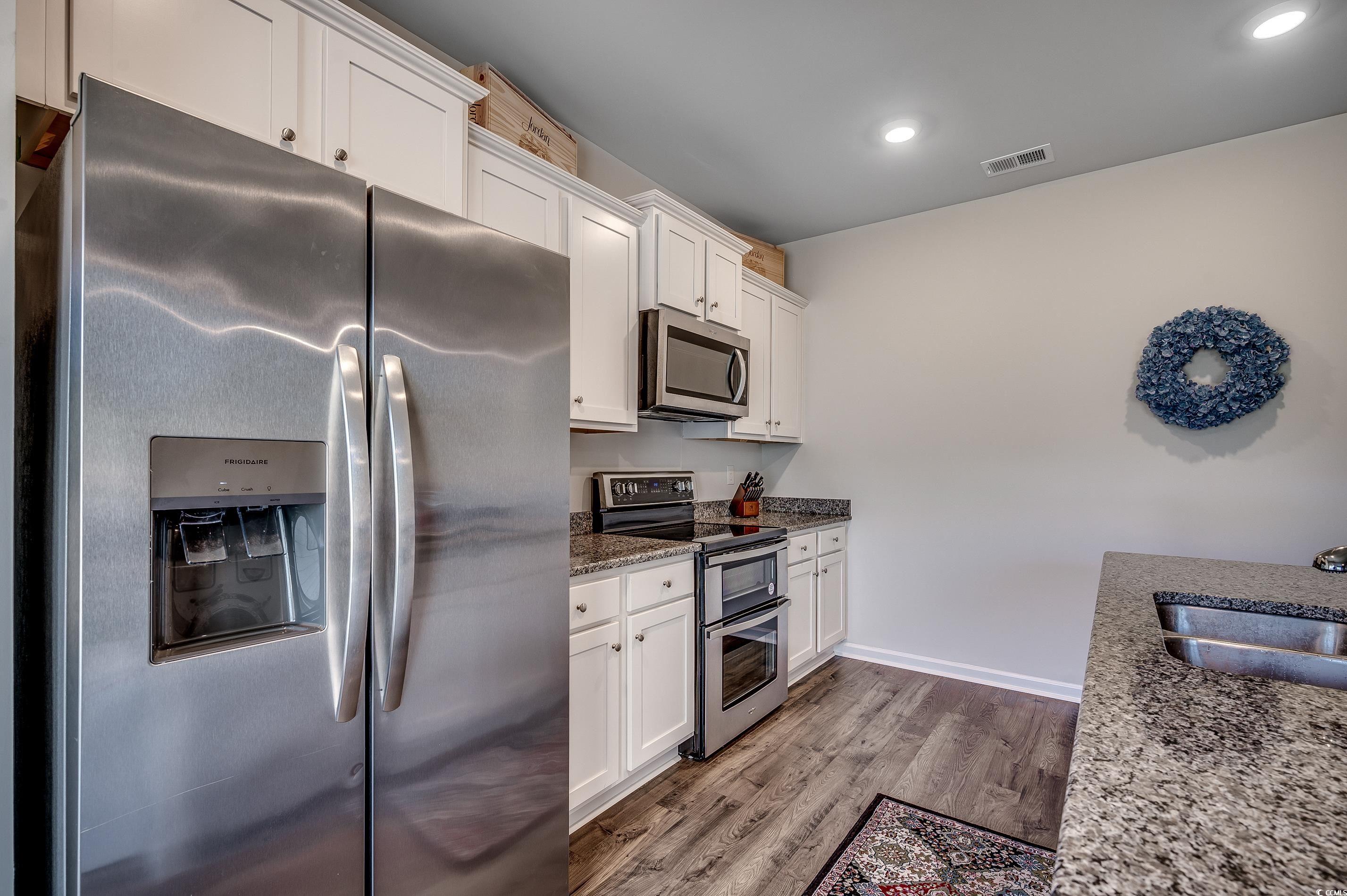 2924 Skylar Drive Myrtle Beach, SC 29577 - Photo 5 of 30 Kitchen featuring stainless steel appliances, white cabinets, wood finished floors, dark stone countertops, and recessed lighting