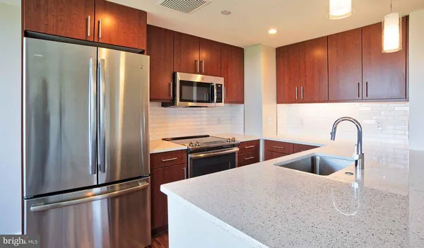 a kitchen with stainless steel appliances granite countertop a refrigerator a sink and a stove