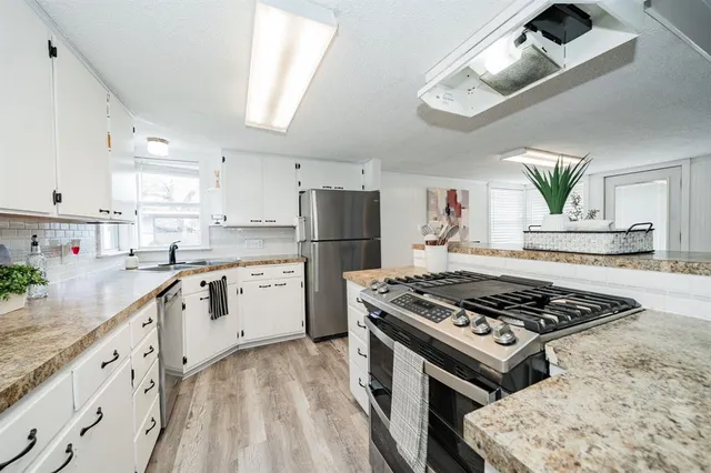 a kitchen with granite countertop a stove a sink dishwasher and a refrigerator with wooden floor