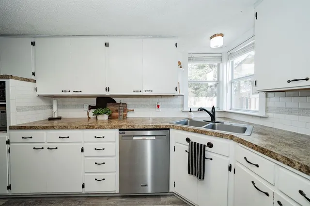 a kitchen with granite countertop a sink a stove and cabinets