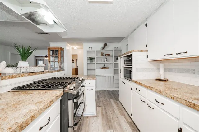 a kitchen with stainless steel appliances granite countertop a lot of counter space and wooden floors