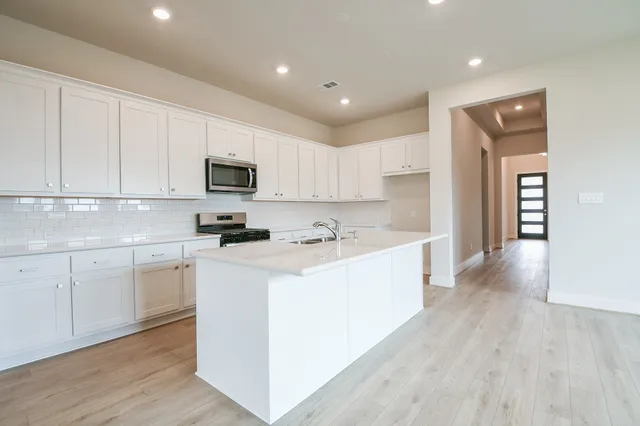 a large kitchen with stainless steel appliances granite countertop a stove a sink and a microwave