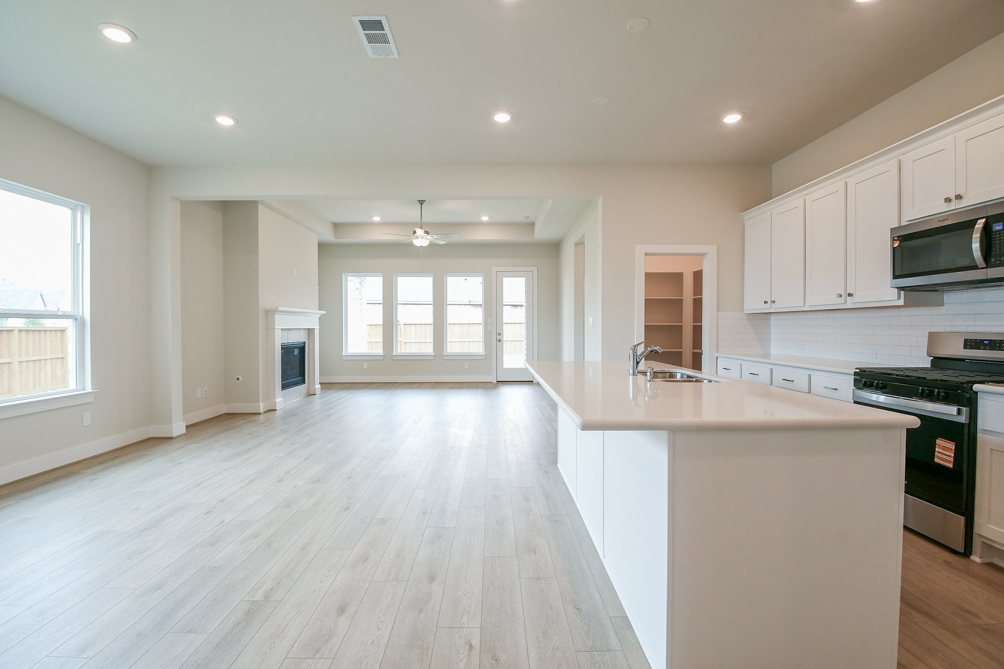 5005 Vly Wind Court Spring, TX 77386 - Photo 18 of 20 a kitchen with stainless steel appliances granite countertop a stove a sink a refrigerator white cabinets and wooden floor next to a window