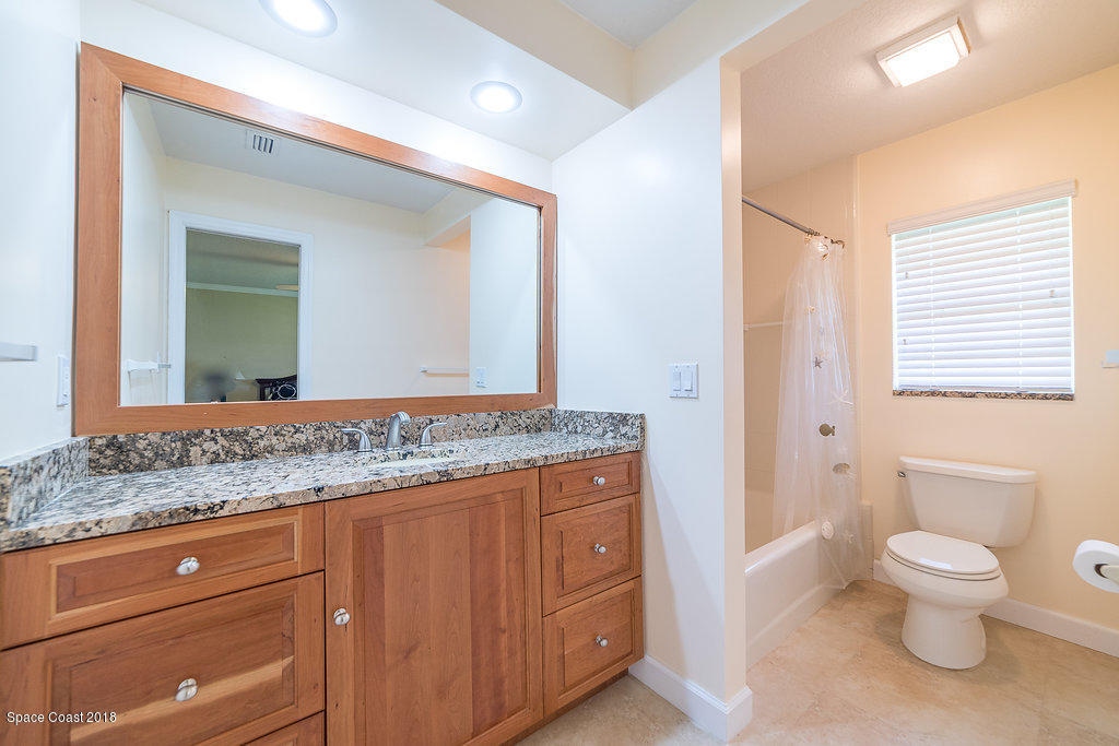 1401 Meadowbrook Road Northeast Palm Bay, FL 32905 - Photo 28 of 46 a bathroom with a granite countertop toilet sink and mirror