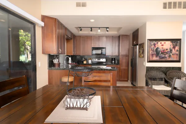 a kitchen with stainless steel appliances granite countertop a refrigerator a stove and a sink with wooden floor