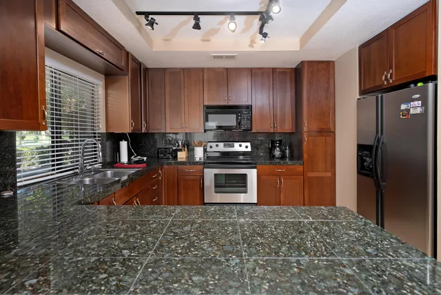 a kitchen with granite countertop a refrigerator stove and sink