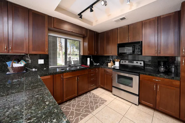 a large kitchen with stainless steel appliances granite countertop a stove sink microwave and cabinets