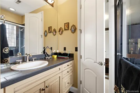 a bathroom with a granite countertop sink a mirror and a shower