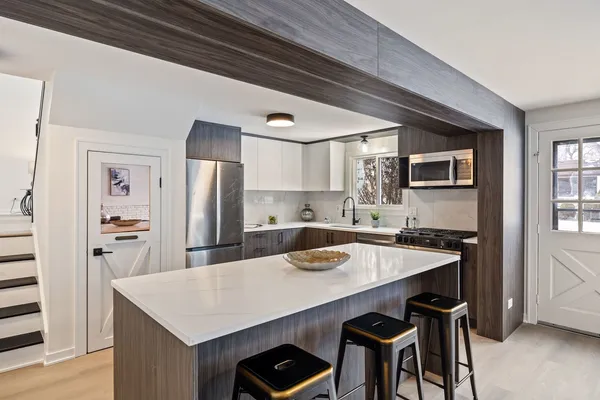 a kitchen with stainless steel appliances a table chairs and refrigerator