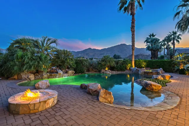 a view of a table and chairs in patio with a fire pit and a yard
