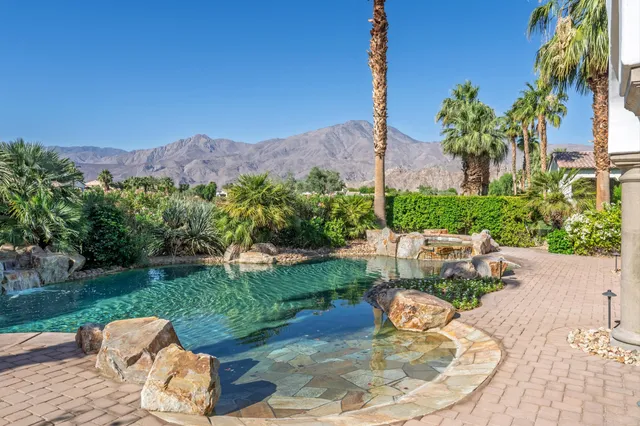 a backyard of a house with table and chairs potted plants and large tree