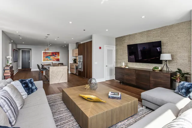 a kitchen with stainless steel appliances granite countertop a stove top oven a sink a dining table and chairs with wooden floor