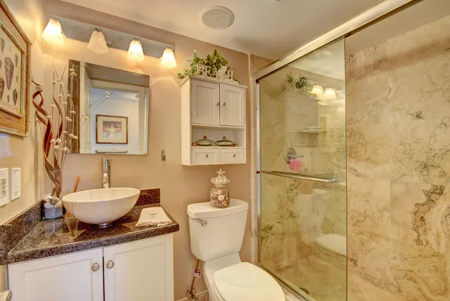a bathroom with a granite countertop sink toilet a mirror and shower