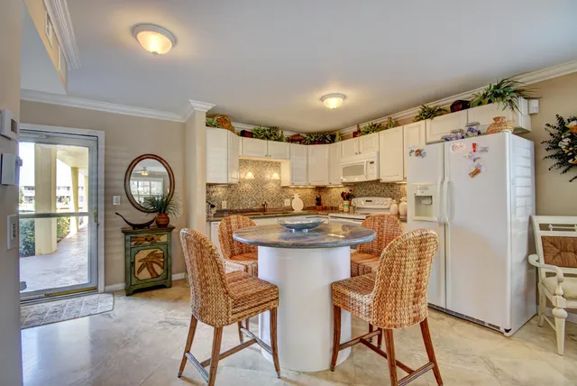 a kitchen with granite countertop a refrigerator a stove a dining table and chairs