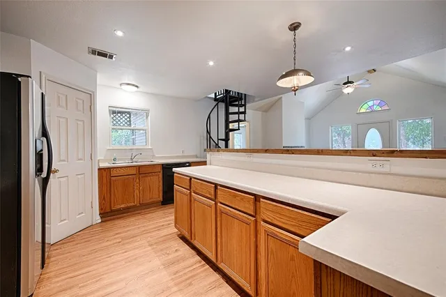 a kitchen with stainless steel appliances granite countertop a refrigerator a sink dishwasher a oven and a dining table with wooden floor