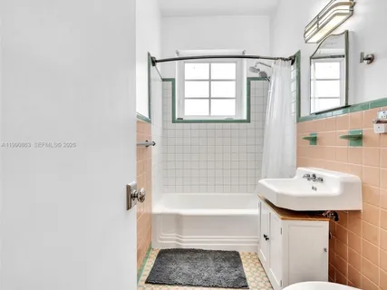 a view of a hallway with wooden floor and a bathroom