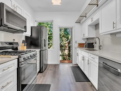 a kitchen with stainless steel appliances a stove sink microwave refrigerator and cabinets