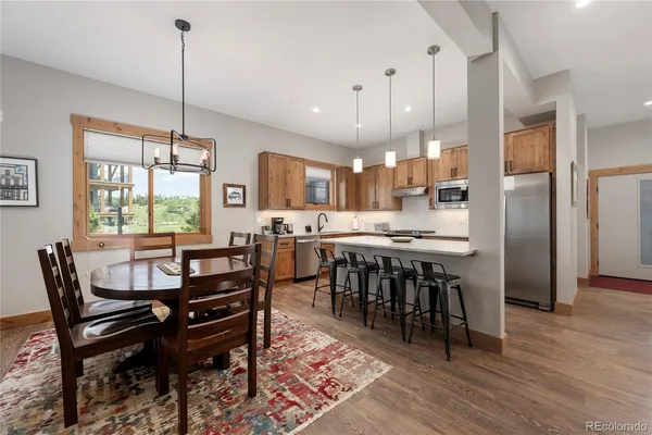 a kitchen with stainless steel appliances granite countertop a stove a sink dishwasher a refrigerator and a dining table with wooden floor