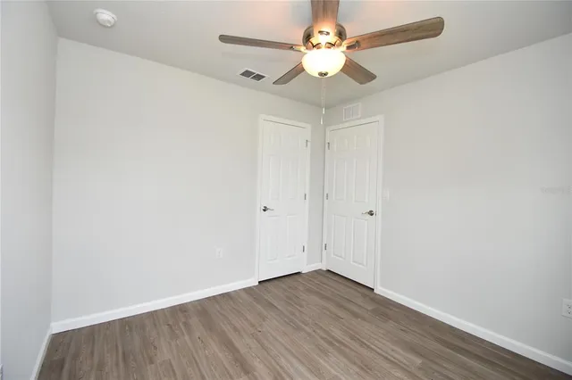 an empty room with wooden floor and ceiling fan