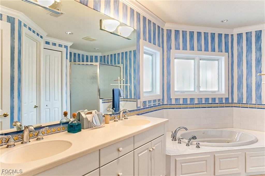 2729 Wulfert Road Sanibel, FL 33957 - Photo 20 of 31 a bathroom with double vanity sinks a mirror and a bathtub