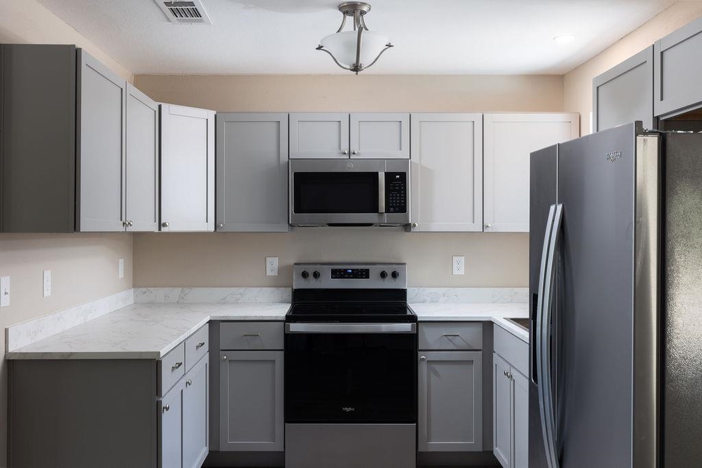 3941 Baybrook Drive Pace, FL 32571 - Photo 7 of 28 a kitchen with stainless steel appliances a refrigerator stove and microwave