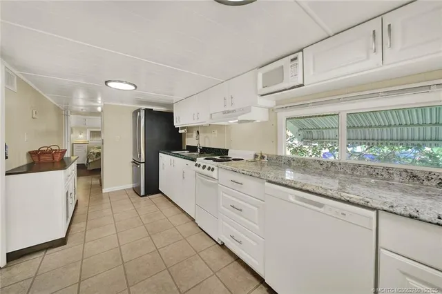 a large white kitchen with granite countertop a sink and white cabinets