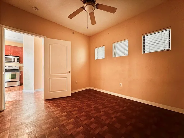 a view of empty room with wooden floor and ceiling fan