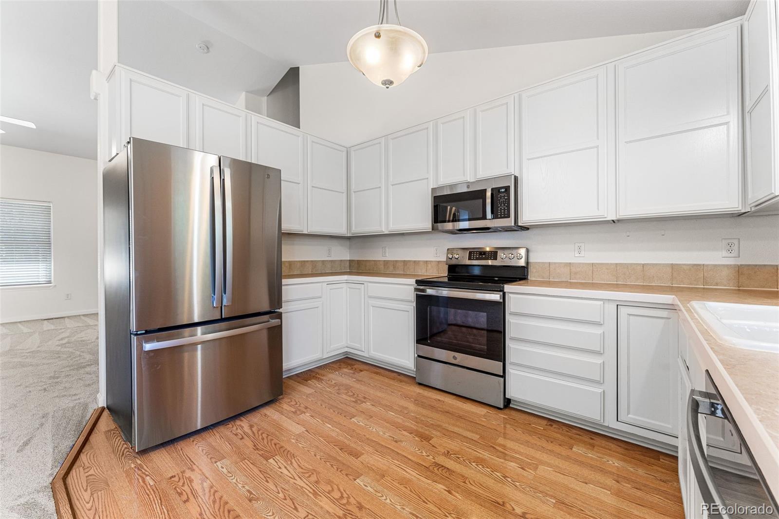 400 Sorrel Drive Windsor, CO 80550 - Photo 4 of 37 a kitchen with a refrigerator stove and white cabinets