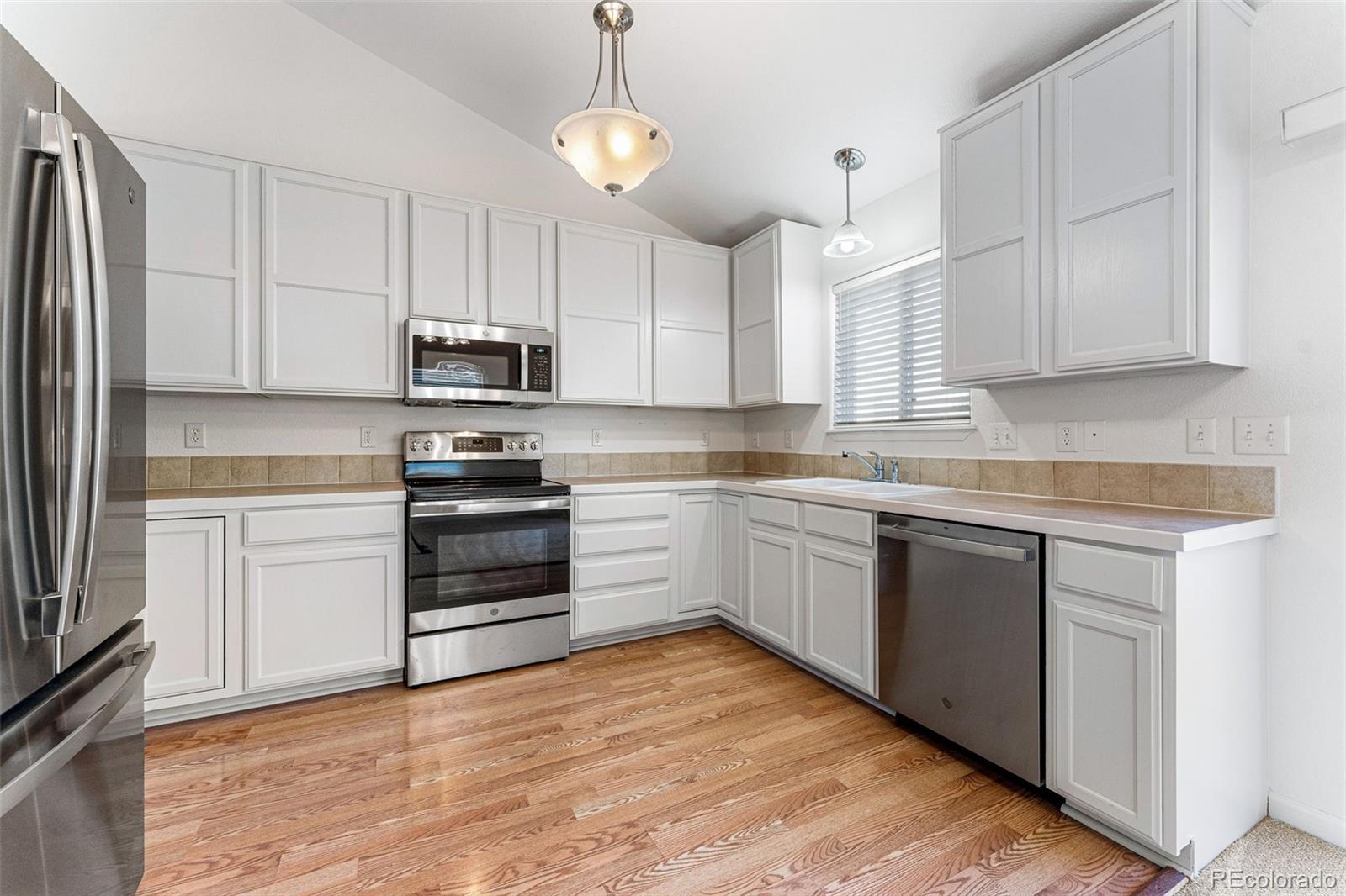 400 Sorrel Drive Windsor, CO 80550 - Photo 5 of 37 a kitchen with granite countertop a stove a sink and a refrigerator