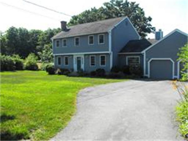 a view of a brick house with a big yard plants and large trees