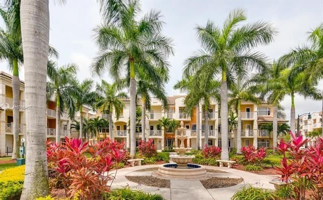 a front view of multi story residential apartment building with yard and sign board