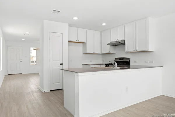 a kitchen with stainless steel appliances granite countertop a refrigerator sink and white cabinets