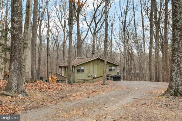 a view of a house with large trees and wooden fence
