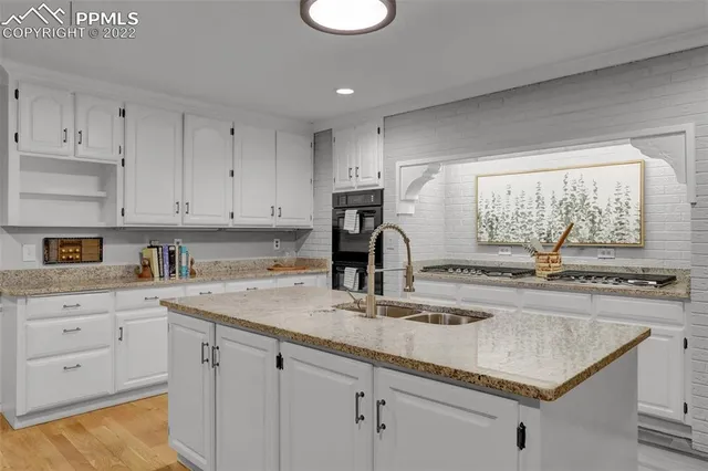 a kitchen with granite countertop a sink a stove and cabinets