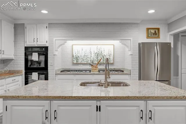 a kitchen with kitchen island granite countertop a sink and a large window