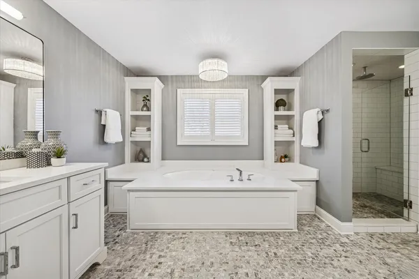 a spacious bathroom with a double vanity sink mirror and bathtub