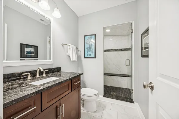 a bathroom with a granite countertop toilet sink shower and mirror
